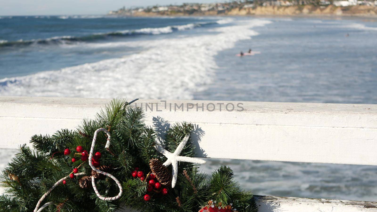 Christmas wreath on pier, New Year on ocean coast, California beach at Xmas. by DogoraSun