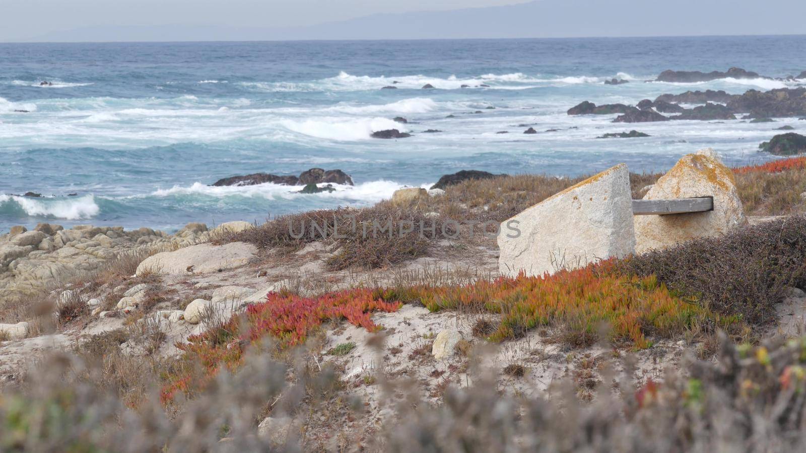 Rocky craggy ocean coast, sea waves, Monterey California. Wooden empty bench. by DogoraSun