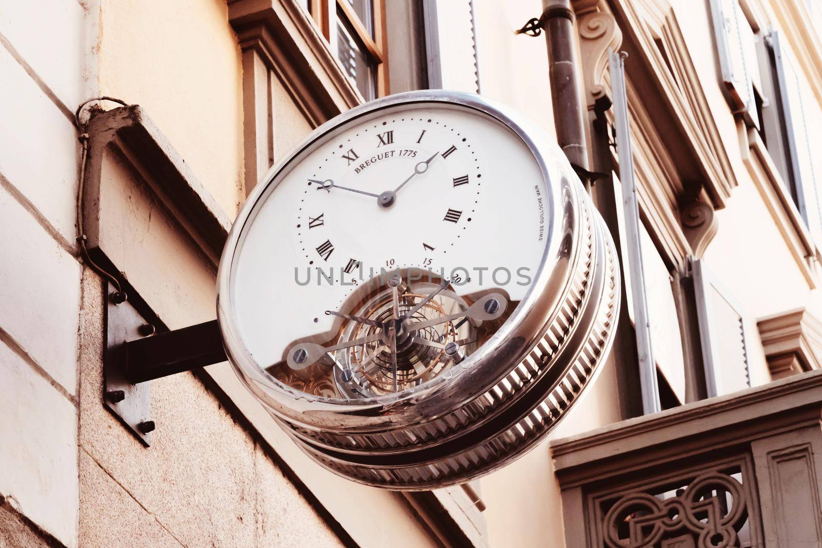 Vintage street clock with roman numerals hanging on the wall of building in center of european city. Milan, Italy - September 26, 2020 by photolime