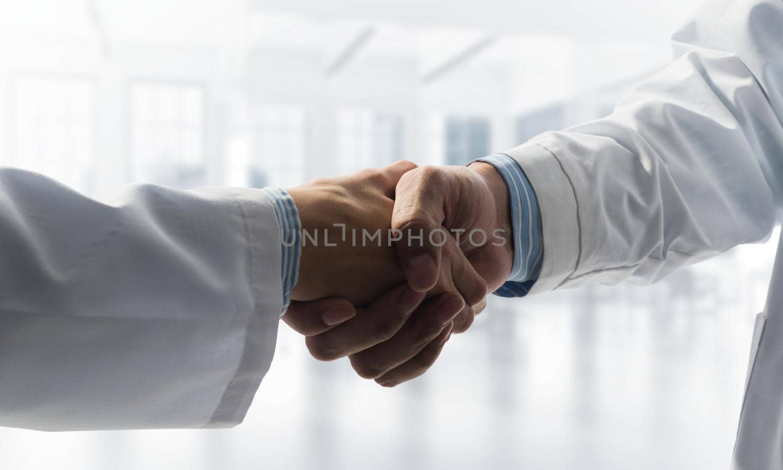 Close-up of the handshake between the two medics. Against the backdrop of the office