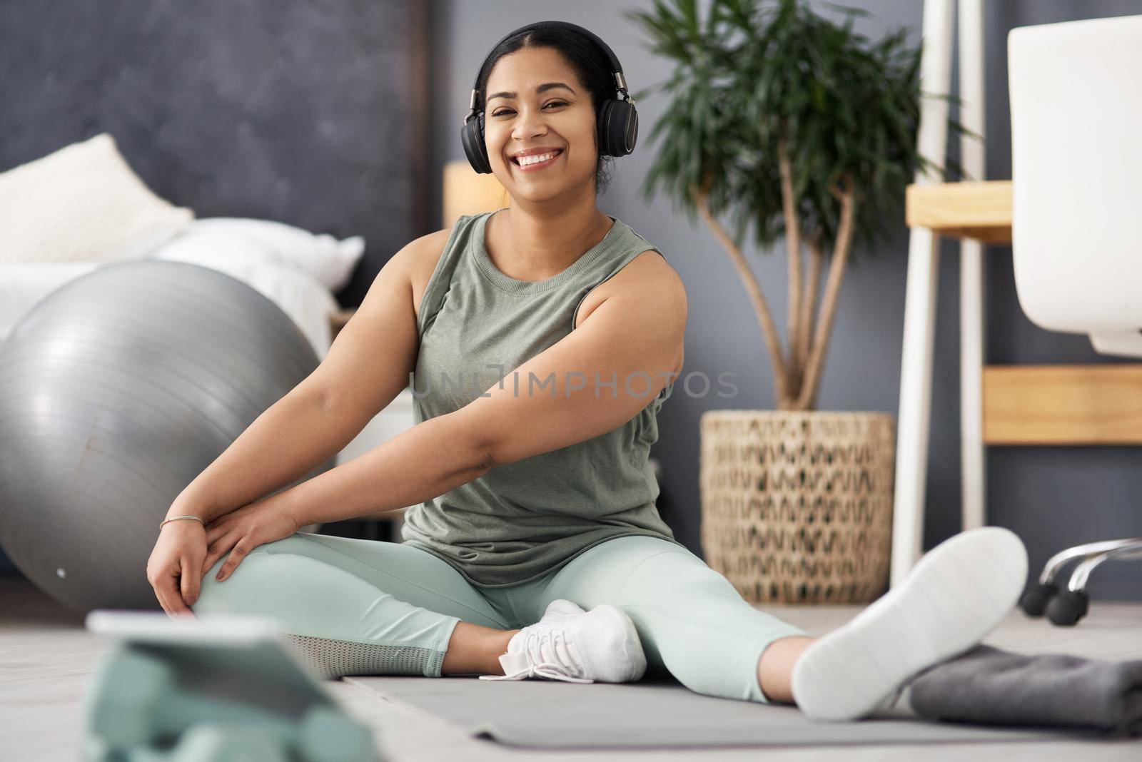 Create healthy habits for yourself. Portrait of a sporty young woman stretching her legs while exercising at home. by YuriArcurs