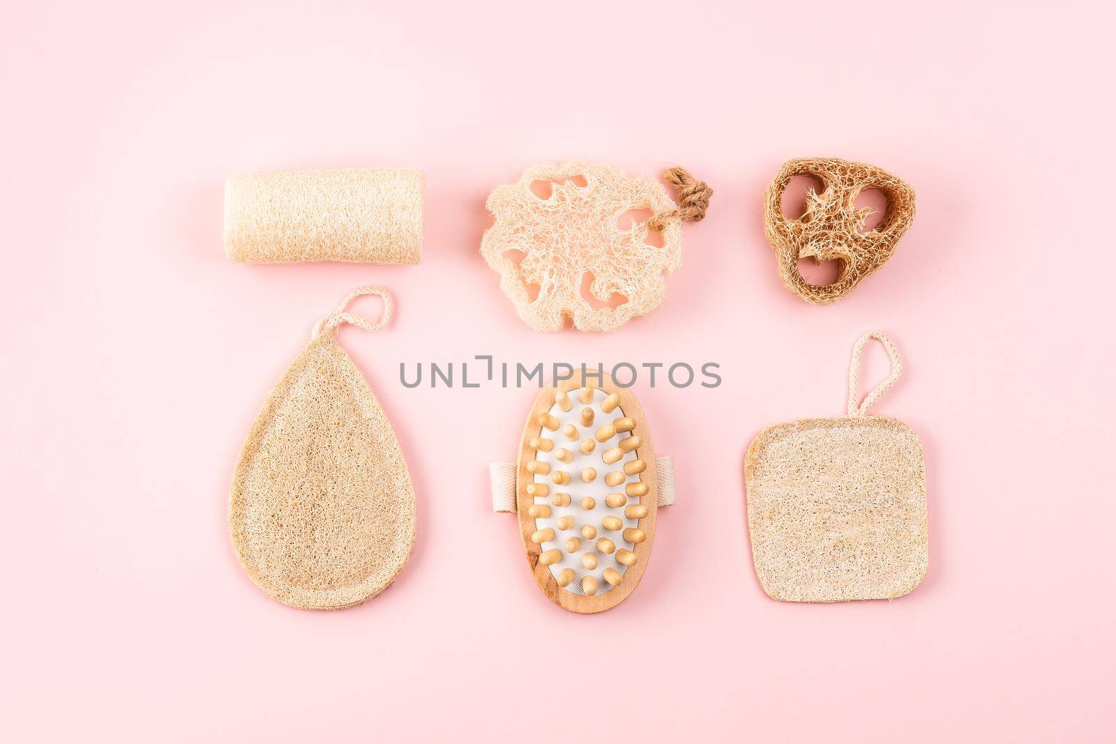 Bathroom accessories, natural loofah sponge, wooden brush on pink background. Zero waste and plastic free concept, sustainable bathroom and lifestyle. Flat lay hygiene products.