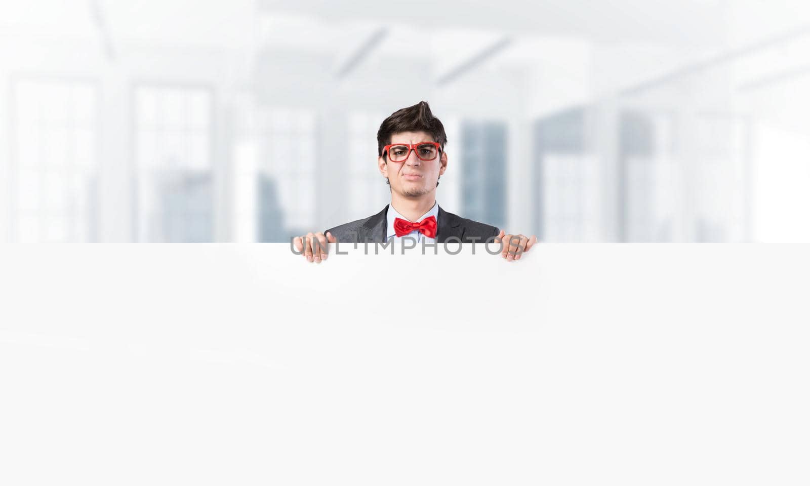 Young businessman holds a banner in front of him with two hands. Place for text