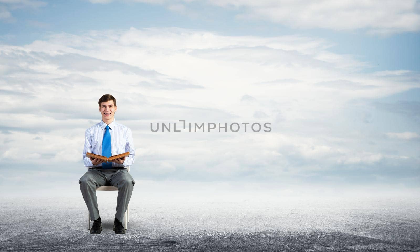 young businessman with book on office chair