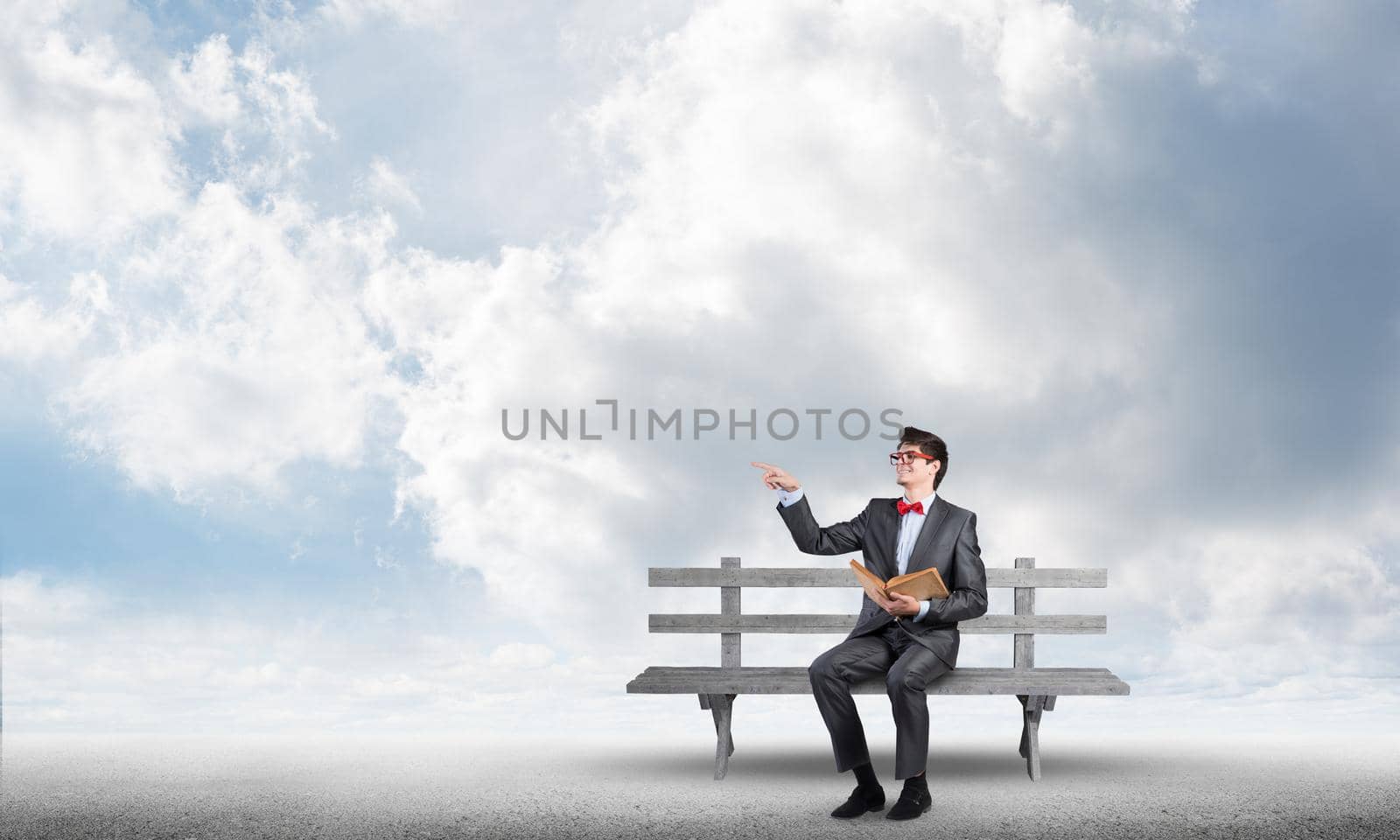 Student sits on a bench, holding a book. Traditional education concept