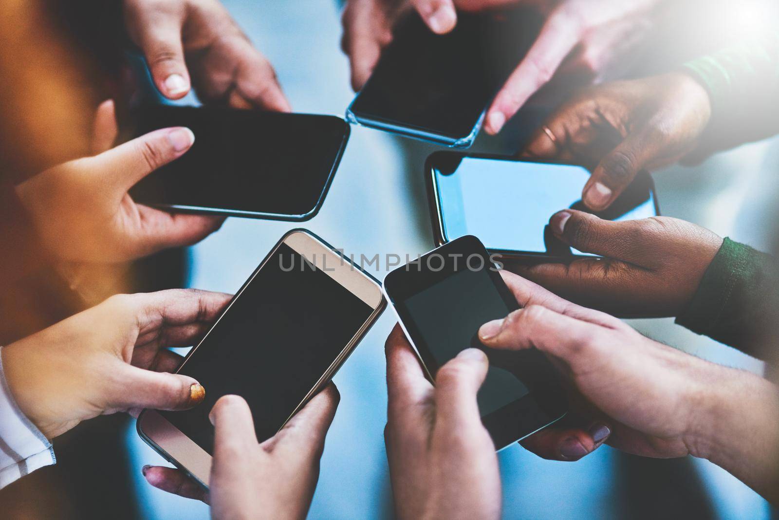 Get connected with the people in your social network. Cropped shot of a group of people using their phones together. by YuriArcurs
