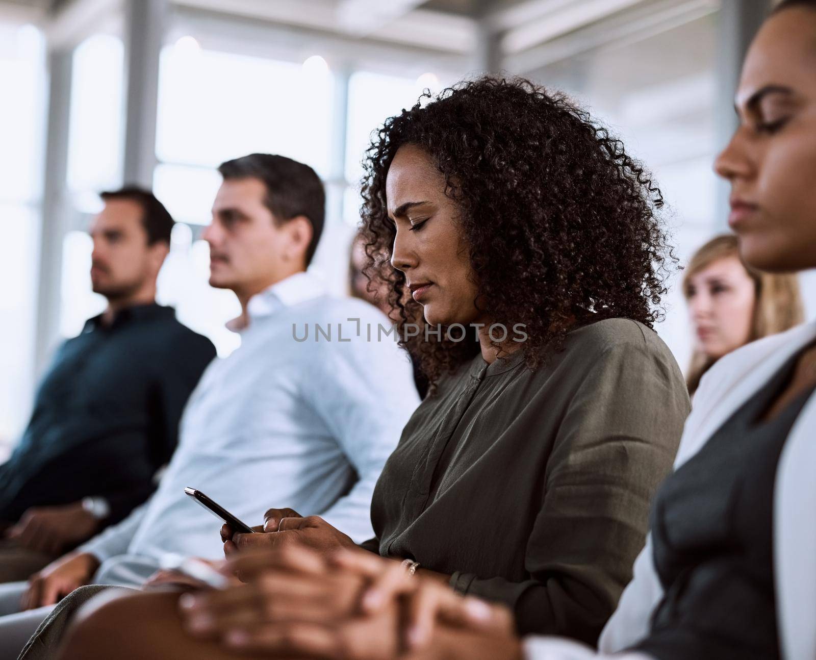 Shot of a businesswoman using her mobile phone during a conference.