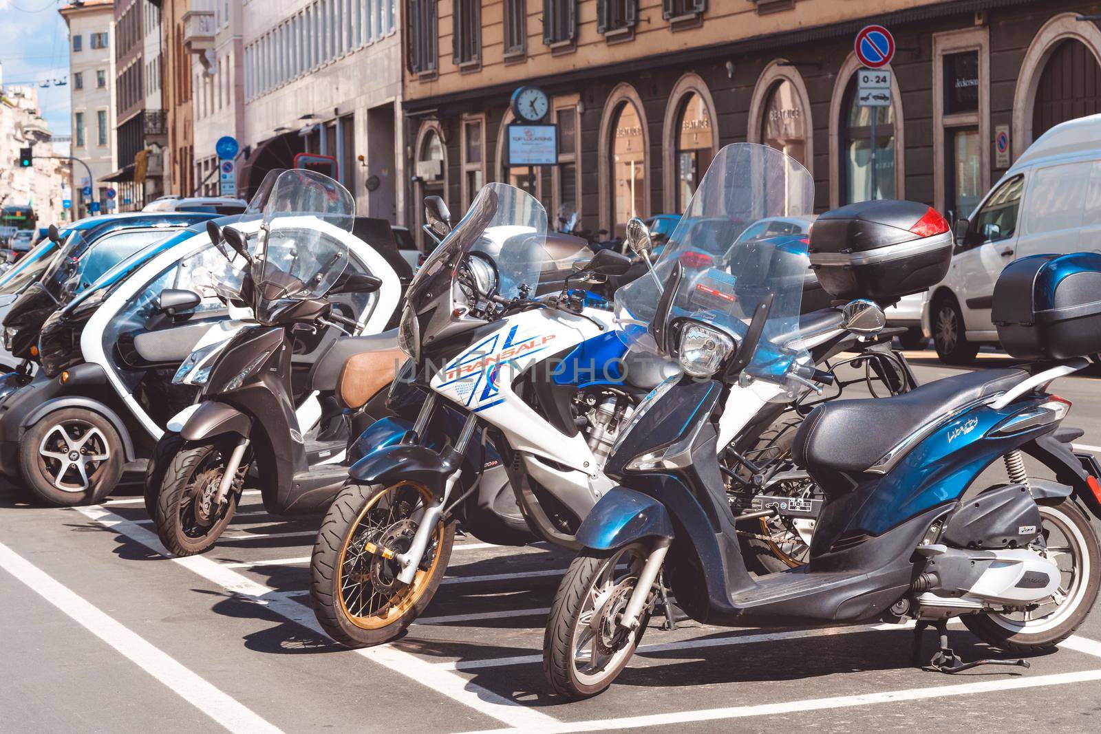 Motorcycles parked in a row in european city center. Motorbike group parking on street during adventure journey. Motorcyclists commuter or commuting concept. Milan, Italy - September 24, 2020.