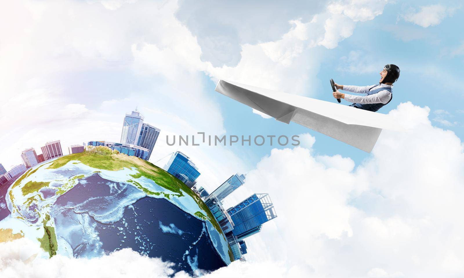 Businessman in aviator hat sitting in paper plane and holding steering wheel. Pilot driving paper plane in cloudy blue sky. Spherical view of modern city with high skyscrapers and sea line.