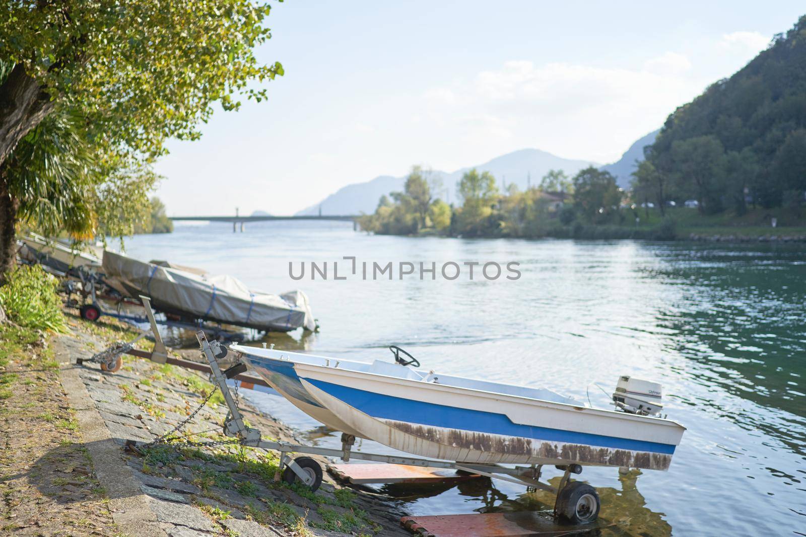 Docked boats on the lake Como district in Italy on sunny day. Alp mountains on background. Lecco, Italy - October 17, 2020