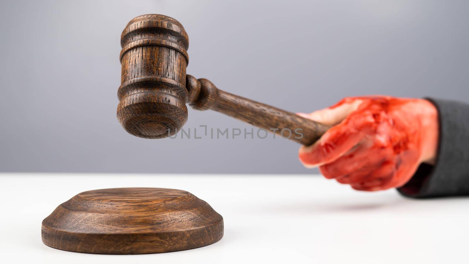 Female judge with bloody hands beats the gavel on a white background. by mrwed54