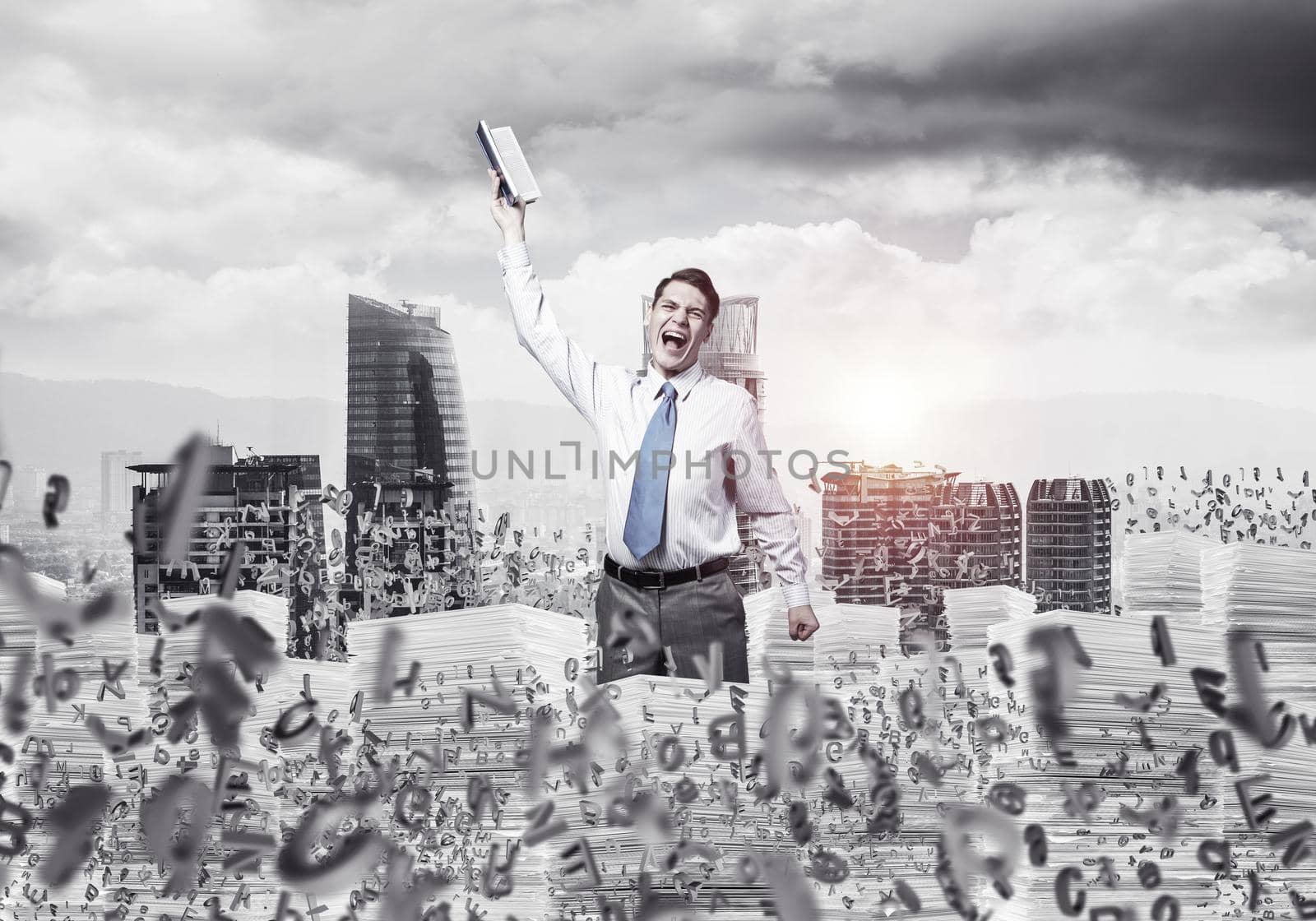Businessman keeping hand with book up while standing among flying letters with cityscape and sunlight on background. Mixed media.