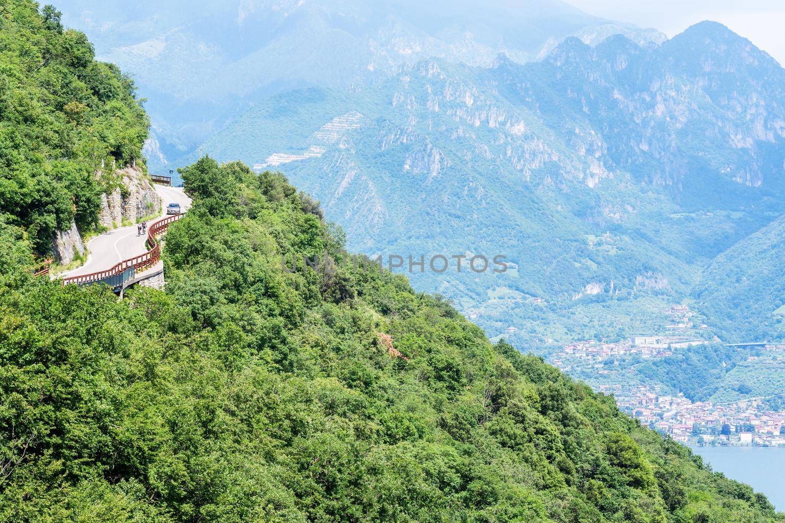 Cycling competition, cyclist athletes riding a race at high speed on road way in alpine mountains, climbing up to top of mountain. Iseo, Italy - June 13, 2020 by photolime