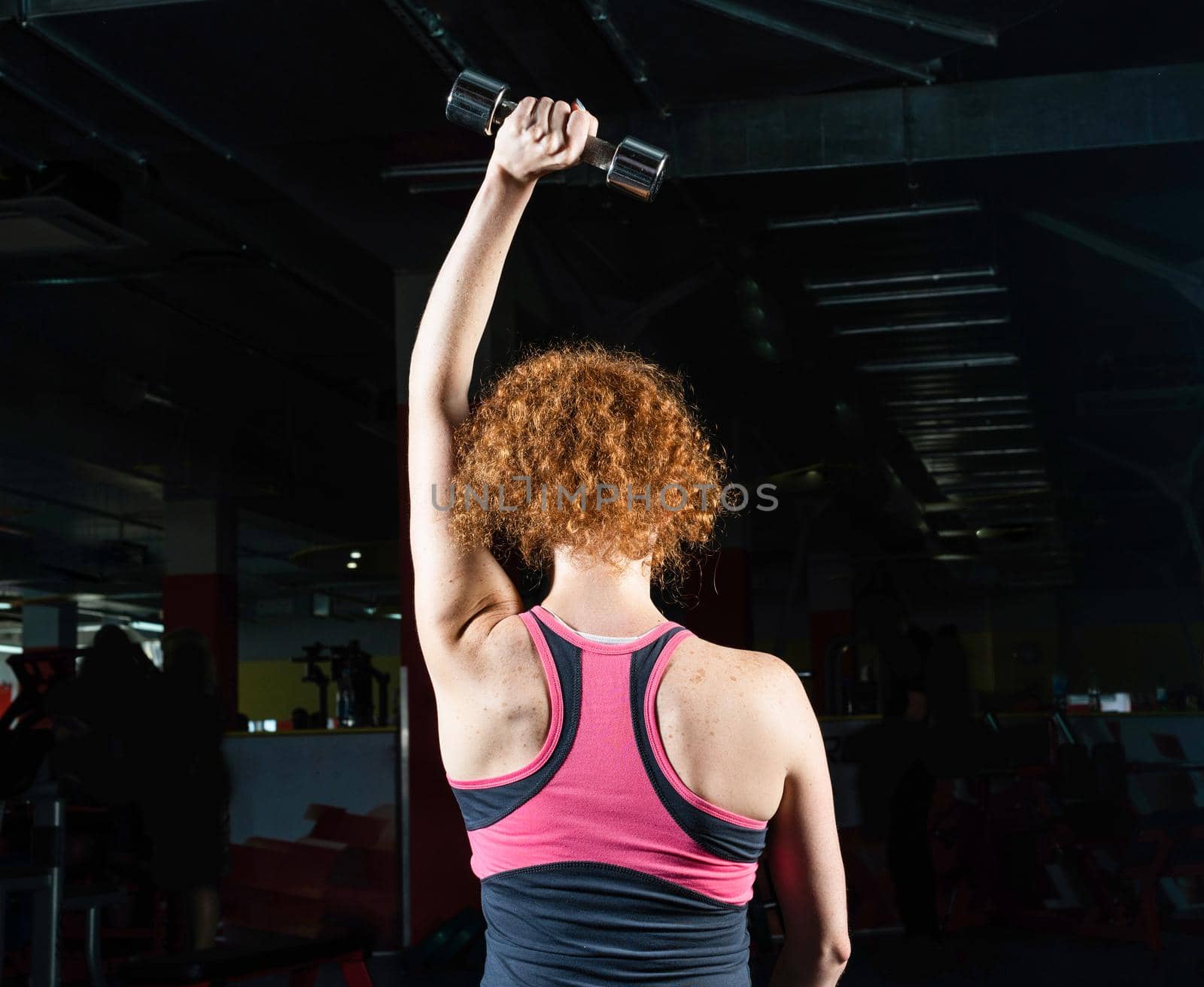 Woman bodybuilder engaged with dumbbells in the gym.