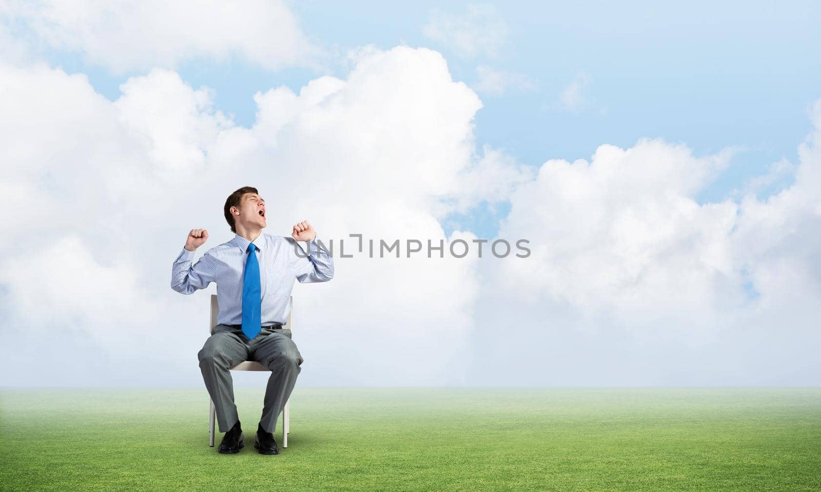 young businessman yawns and stretches while sitting on a chair