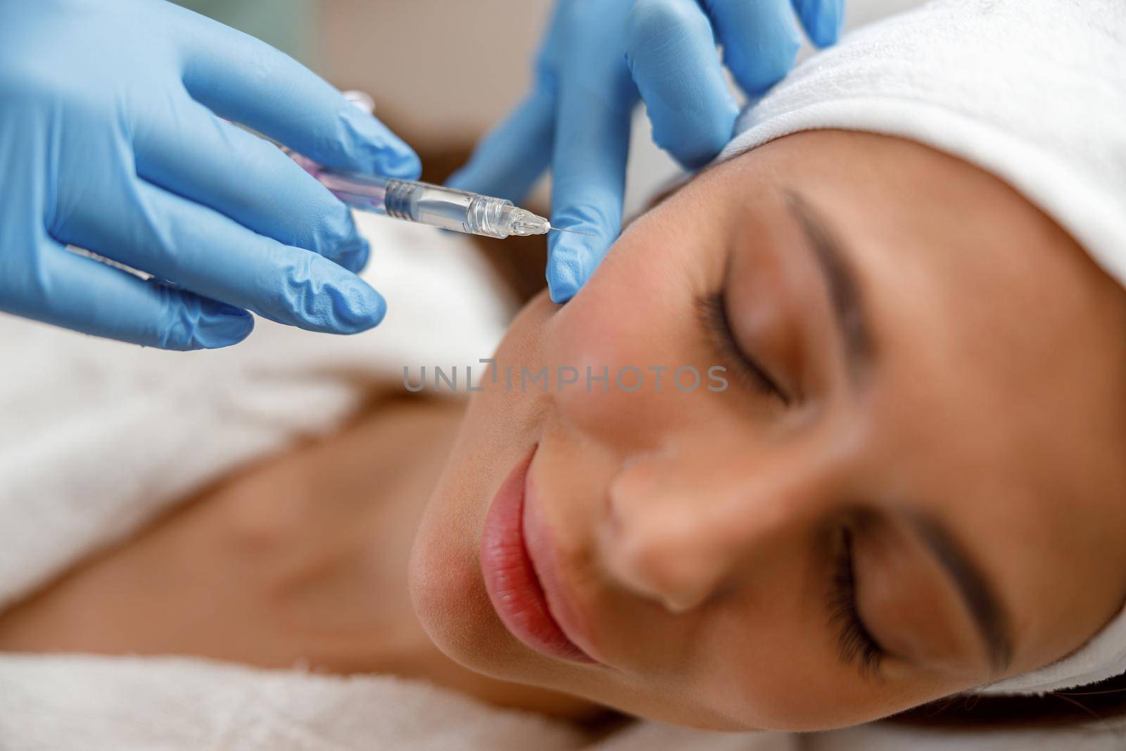 Closeup of young woman receiving hyaluronic acid injection in cheekbones at beauty salon by Yaroslav_astakhov