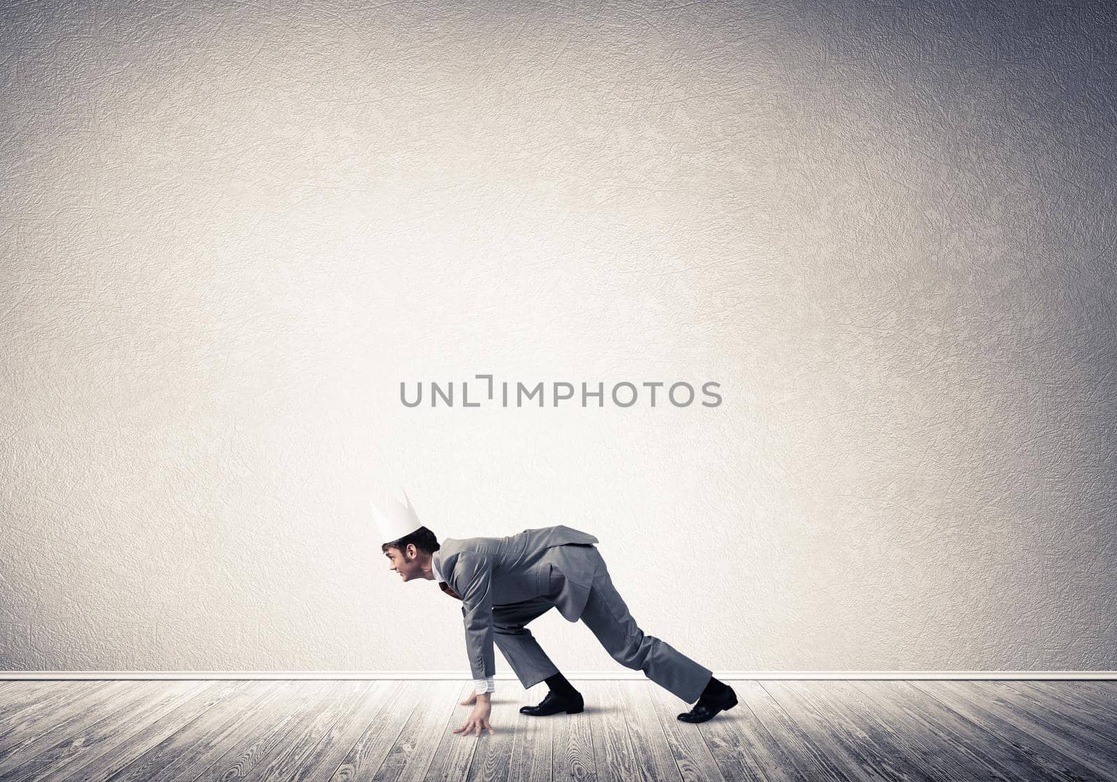 Young handsome businessman wearing white paper crown running in a hurry