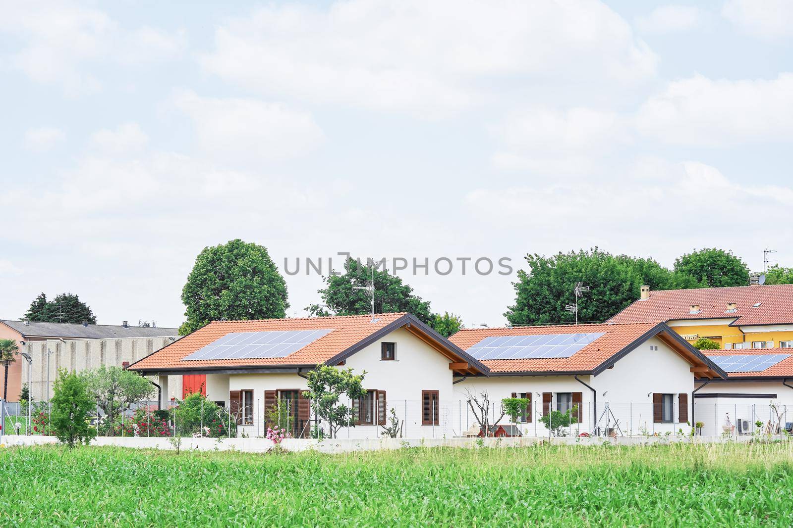 Renewable energy system on roof of traditional houses in contemporary suburban neighborhood in Italy, Europe. Modern and beautiful houses in european style with solar panels on the roof.