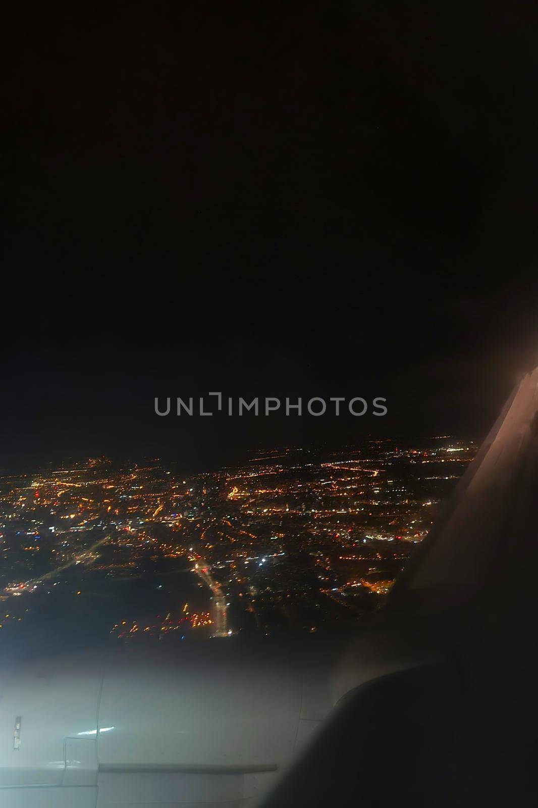 View of the night glowing city from a flying plane