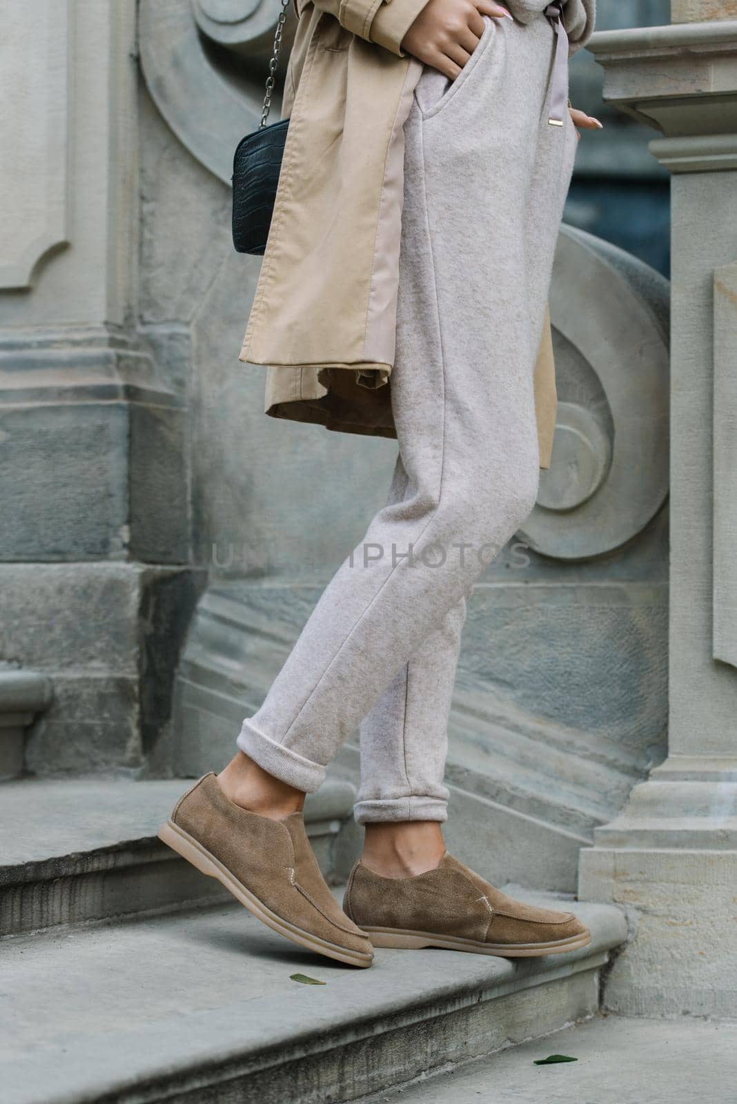 Portrait of fashionable women in beige pants and trench coat posing on the stone stairs by Ashtray25
