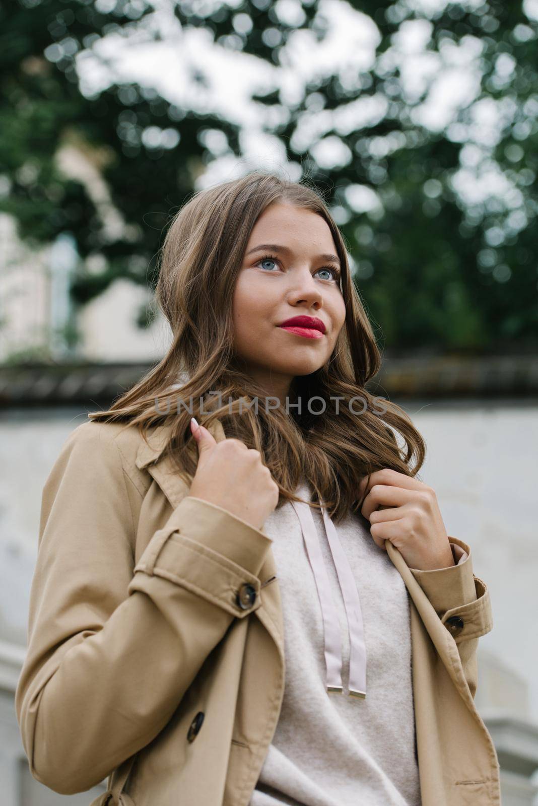 Portrait of fashionable women in beige sports suit and trench coat posing. street look fashion