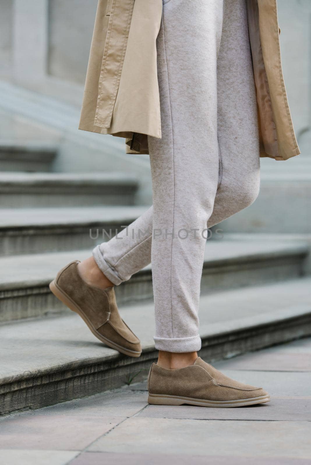 Portrait of fashionable women in beige dress and stylish suede loafer shoes posing in the street