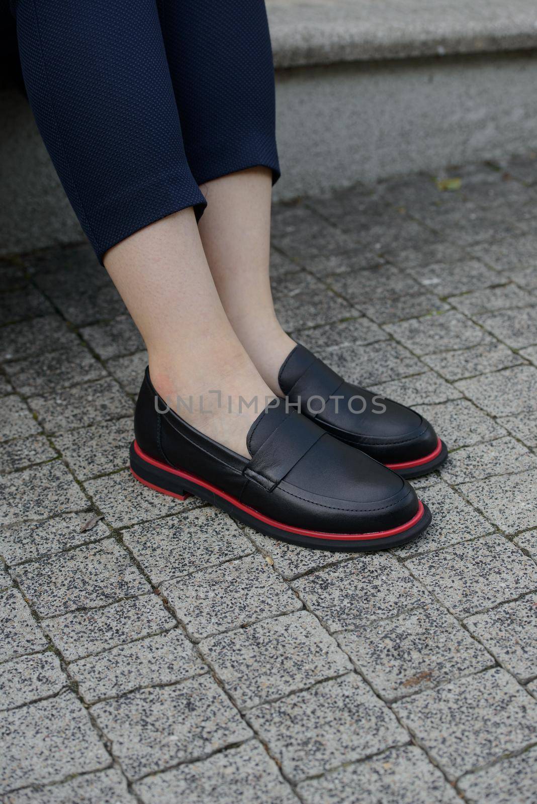 Female fashion concept. Womans legs in a black shoes with red line City lifestyle