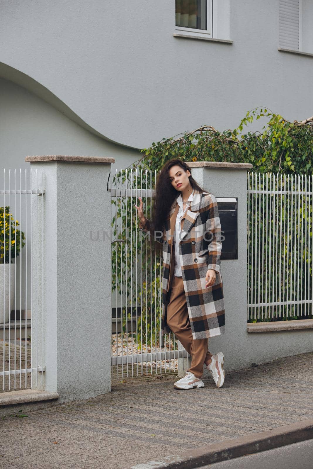 Closeup portrait of young beautiful fashionable woman wearing checkered long coat, beige pants and white blouse . Lady posing on city street. by Ashtray25