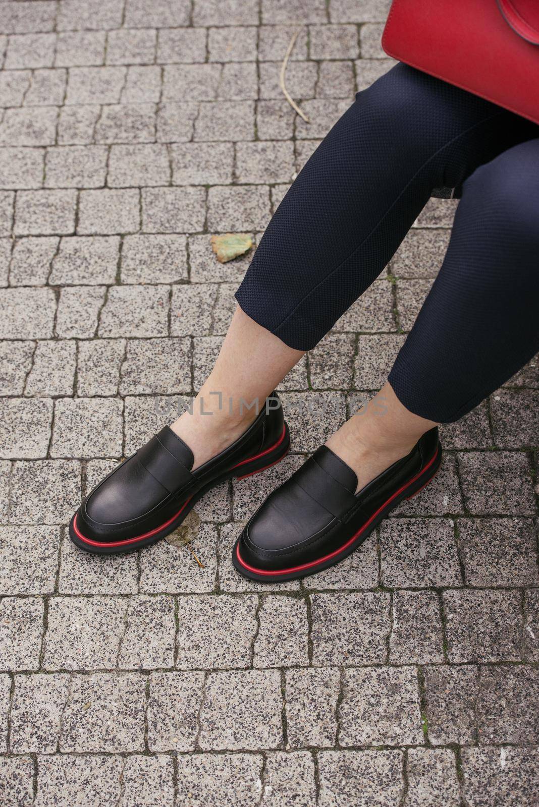 Female fashion concept. Womans legs in a black shoes with red line City lifestyle