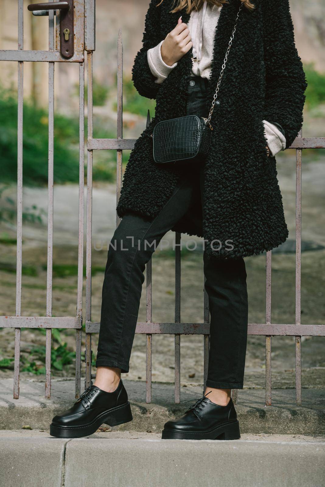 Fashion photo of young gorgeous beautiful woman in black fur coat, jeanse and shoes at city street