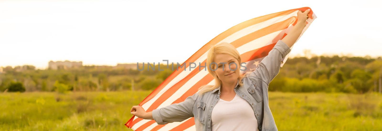 country, patriotism, independence day and people concept - happy smiling young woman with national american flag on field.