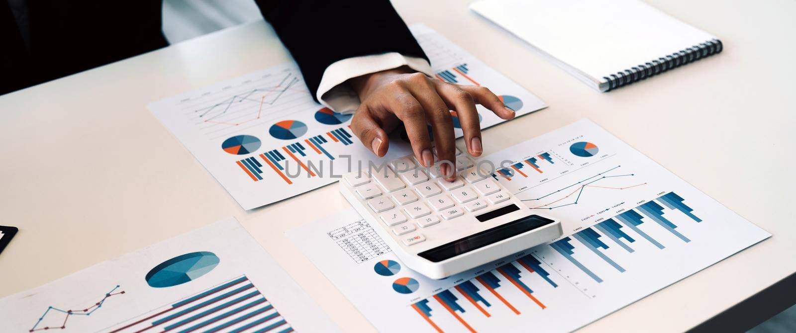 Close up of business accountant woman using calculator to calculate business data, accountancy document at home office. by nateemee