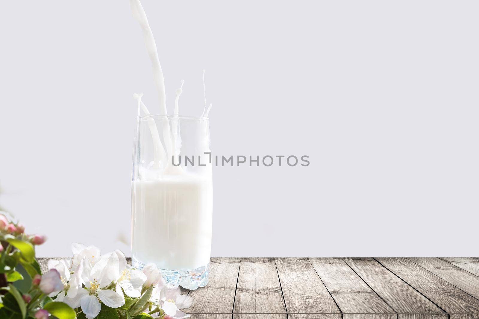 milk pouring into glass on wooden table outdoors