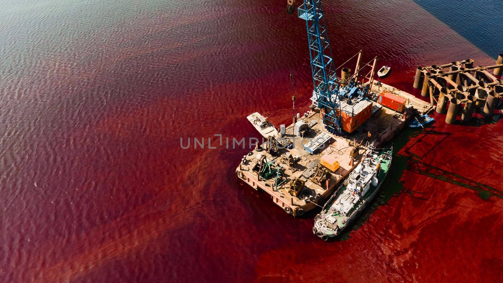 An old rusty red and brown barge in red water. Urban and industrial decay concept