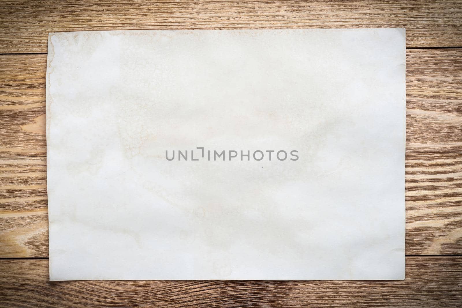 Flat lay wooden table with paper sheet. Blank white a4 format paper. Space for writing and notification. Textured natural wooden background for message. Vintage copy space for creative design.