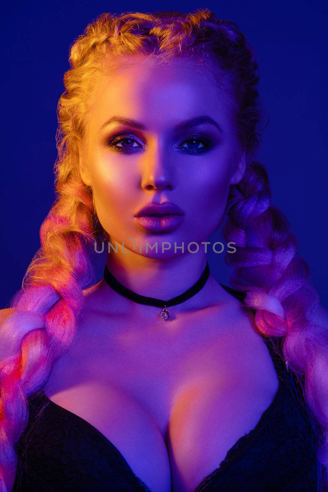 Portrait of seductive young European woman surrounded by evening neon lights medium close-up. Beautiful sexy female fashion model with modern hairstyle isolated at studio black background