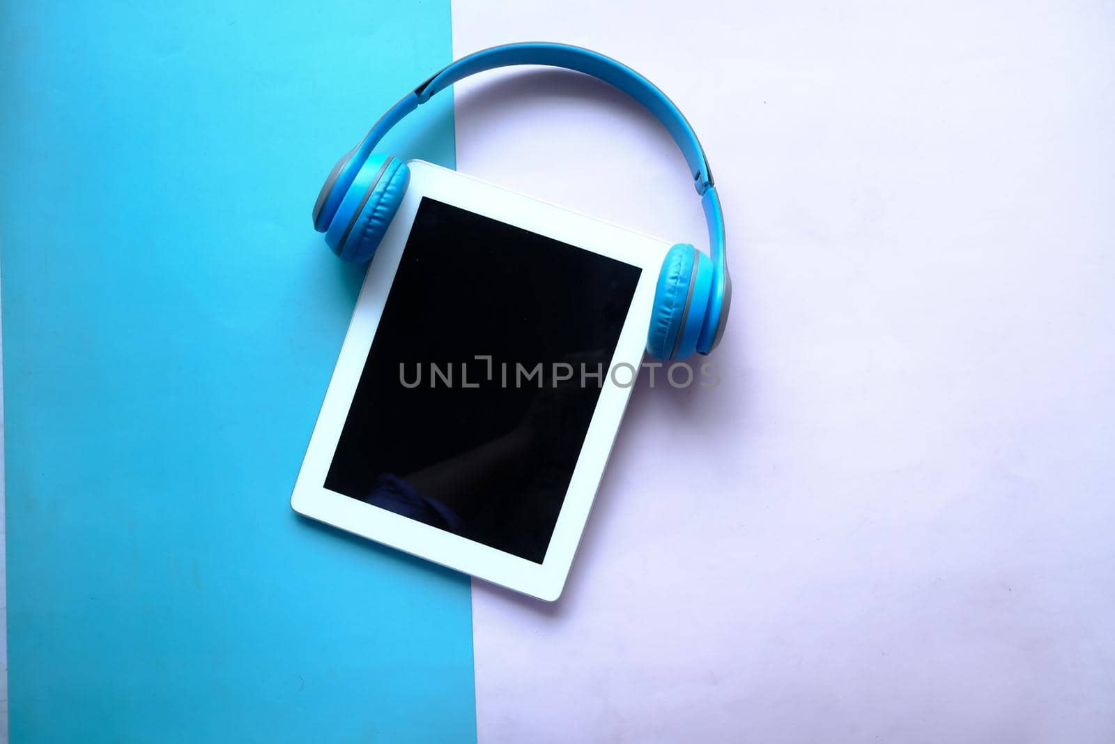 Audio book concept. Headphones and digital tablet on table .