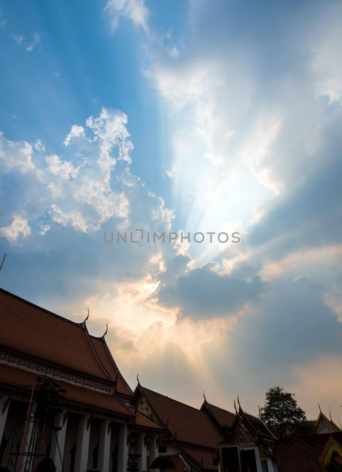 Sun beam behind the sunset clouds over the buddhist temple by Satakorn