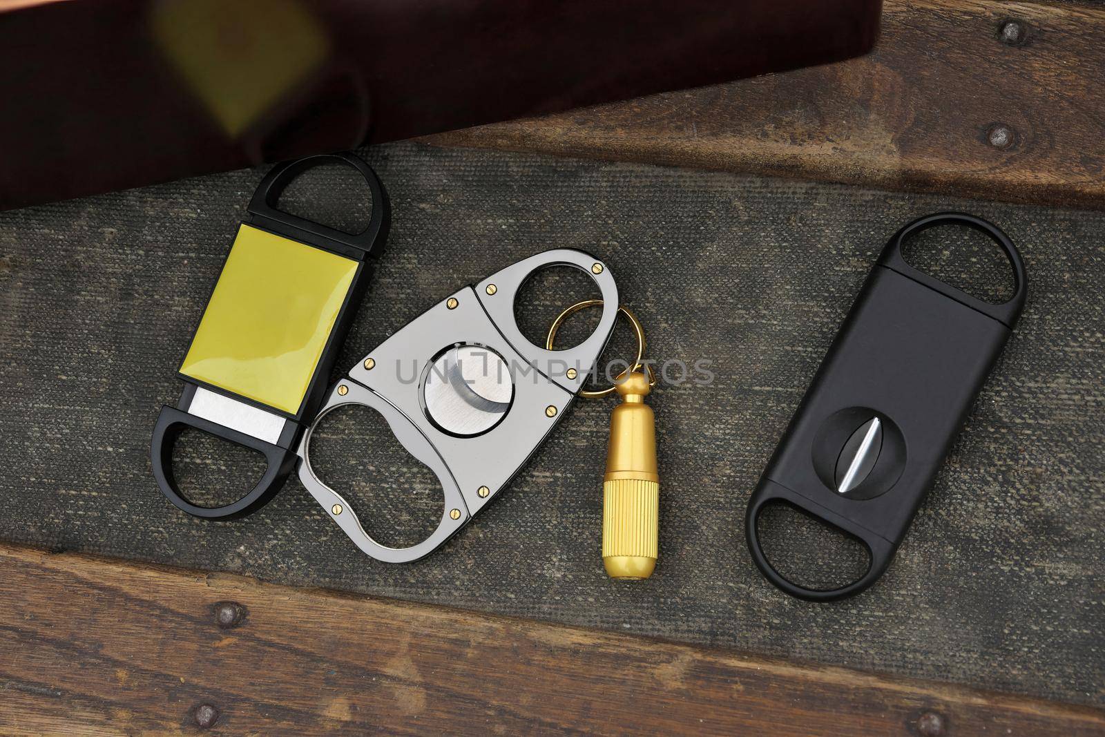 Flatlay Assortment of Cigar Cutters on Rustic Wood Table Beside Cigar Box. High quality photo