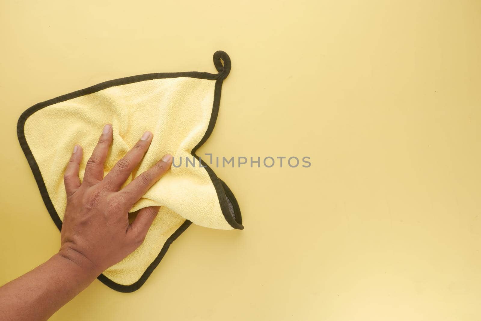 top view of person hand cleaning table with yellow color cloth .