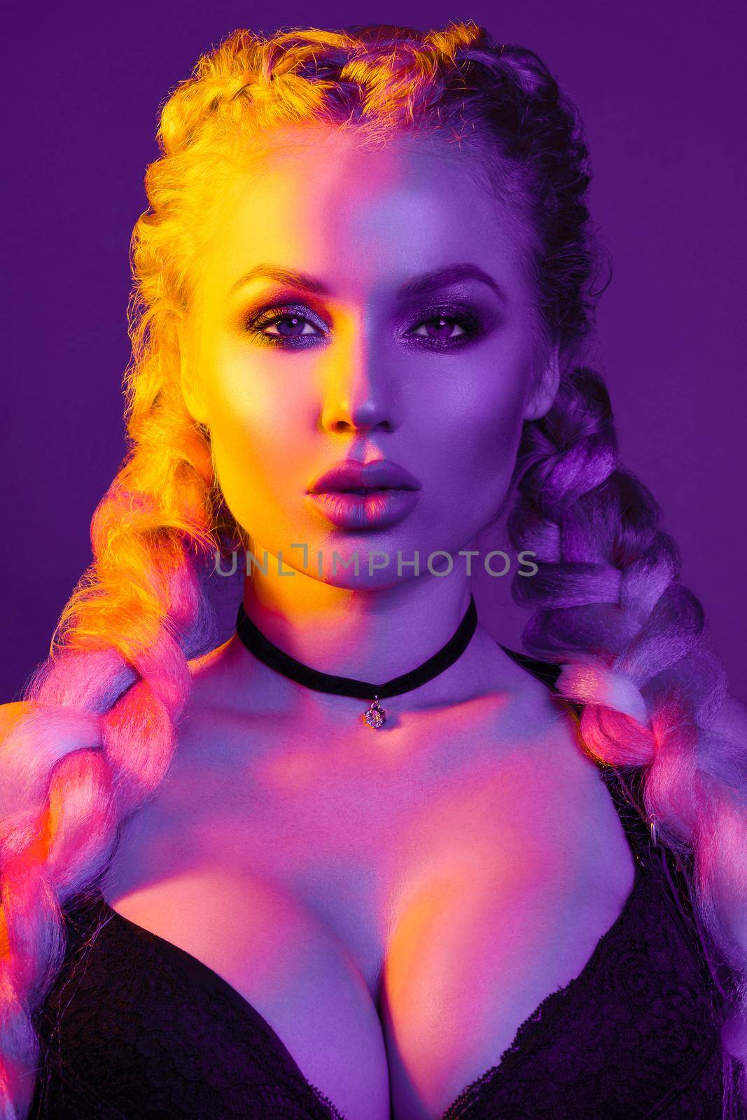 Portrait of seductive young European woman surrounded by evening neon lights medium close-up. Beautiful sexy female fashion model with modern hairstyle isolated at studio black background