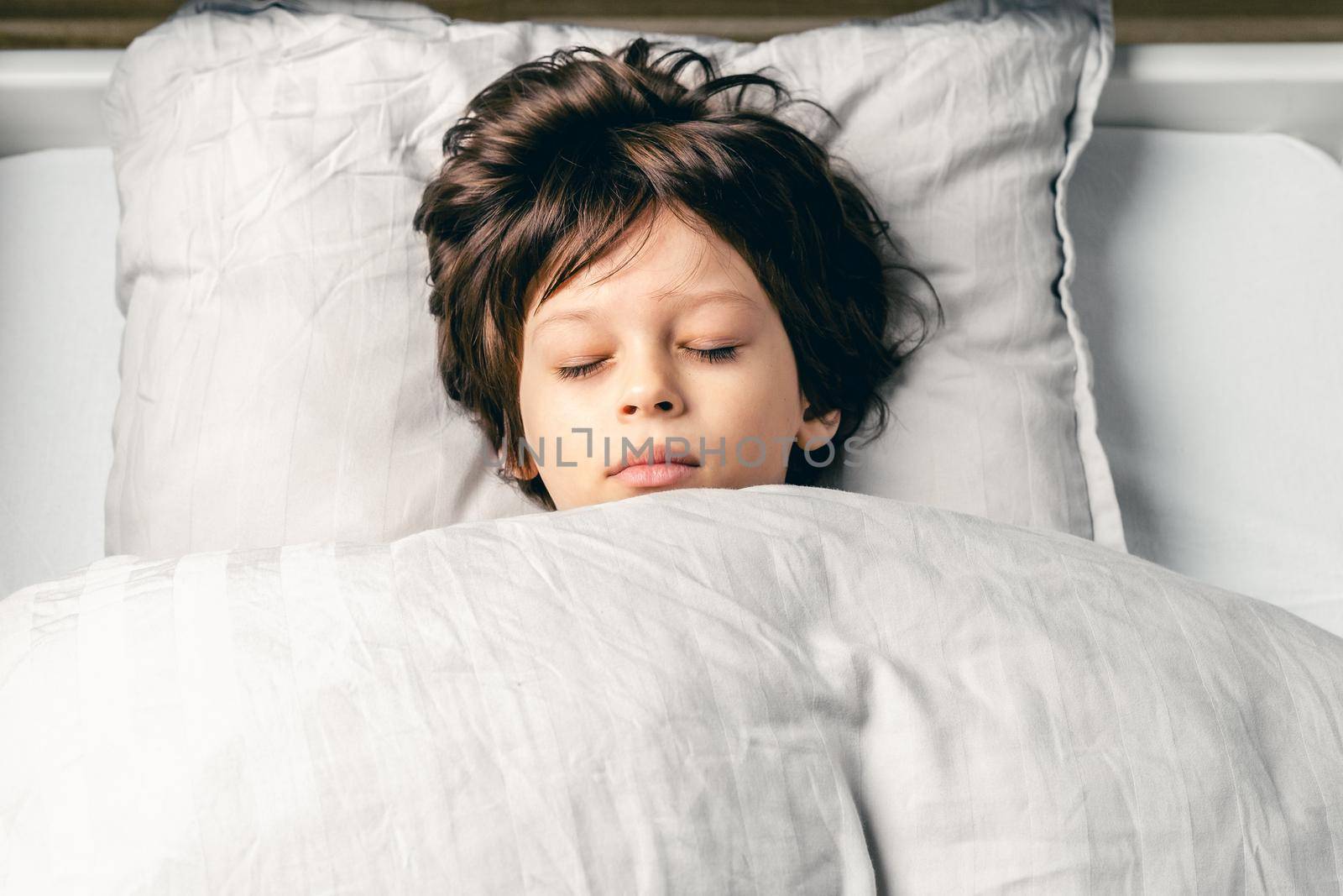 European cute little boy sleeping in the bed at home by Syvanych