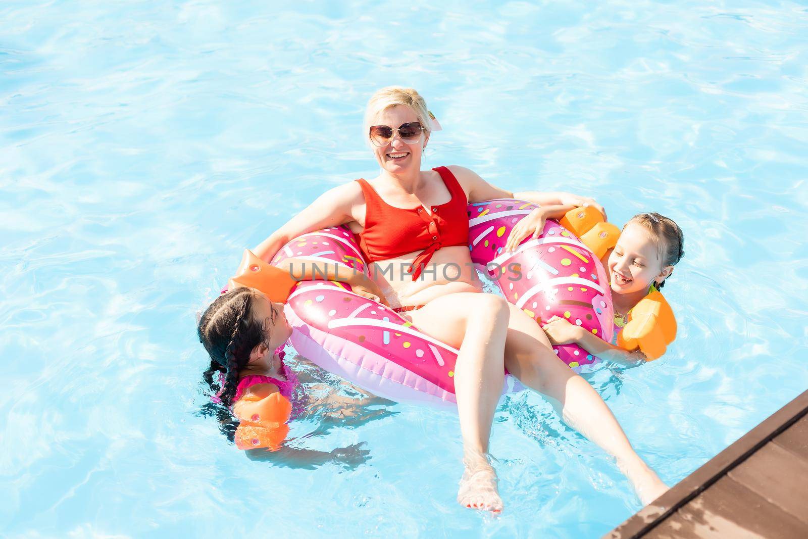 Happy family having fun on summer vacation, playing in swimming pool. Active healthy lifestyle concept.