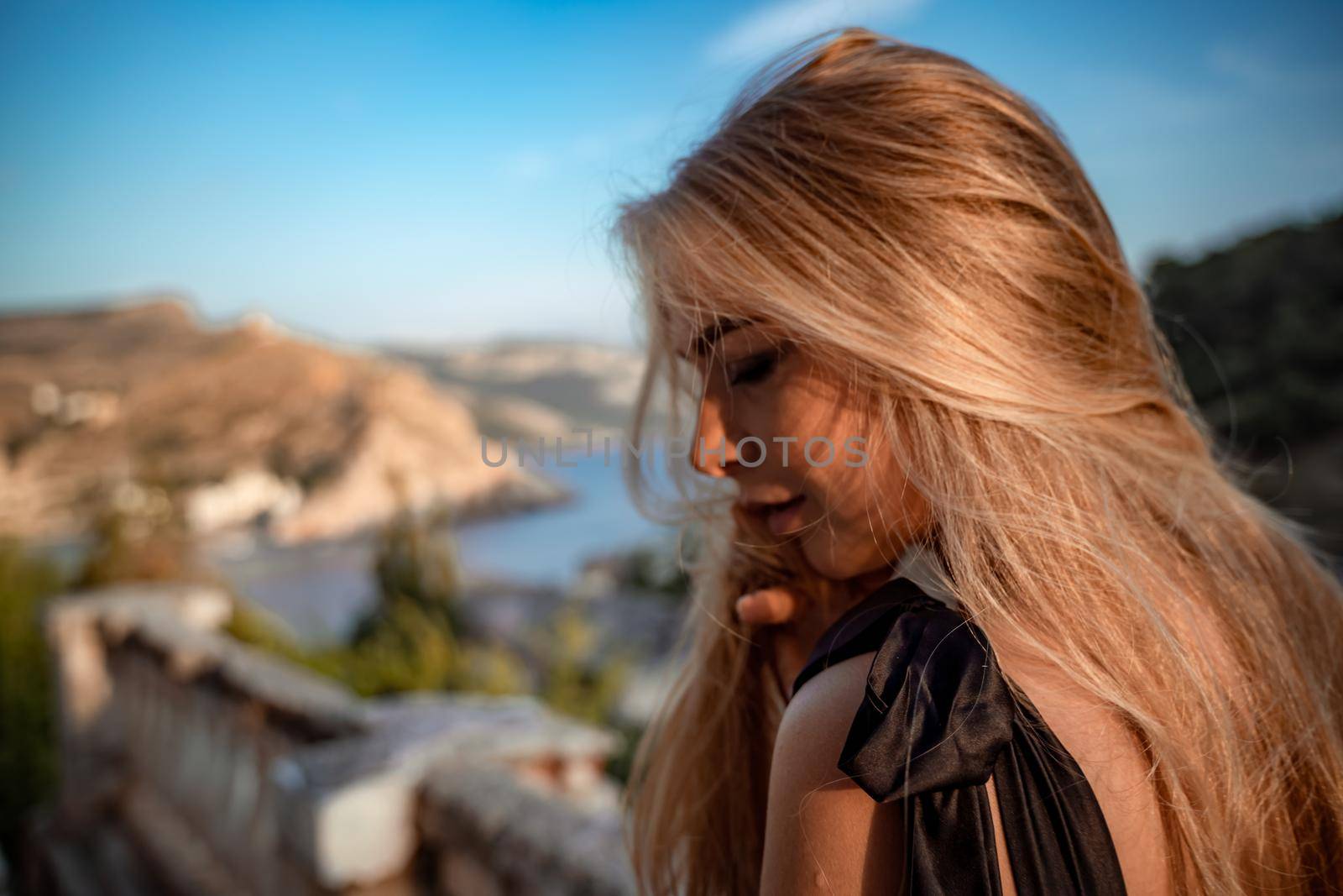 Blonde long hair, nature summer happy adult girl with long blond hair developing in the wind in nature. Dressed in a black top, white skirt