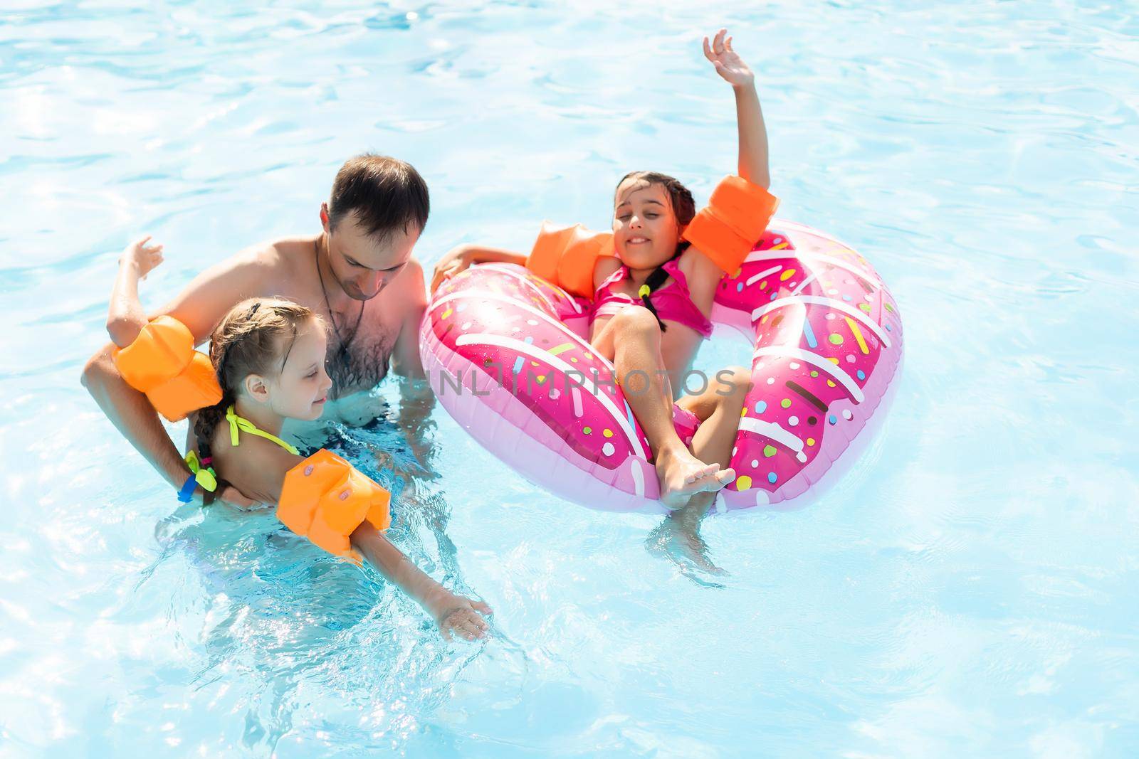 Happy family having fun on summer vacation, playing in swimming pool. Active healthy lifestyle concept.