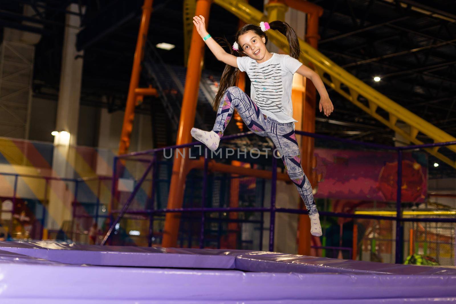 Little child jumping at trampoline in indoors playground. Active toddler girl having fun at sport centre