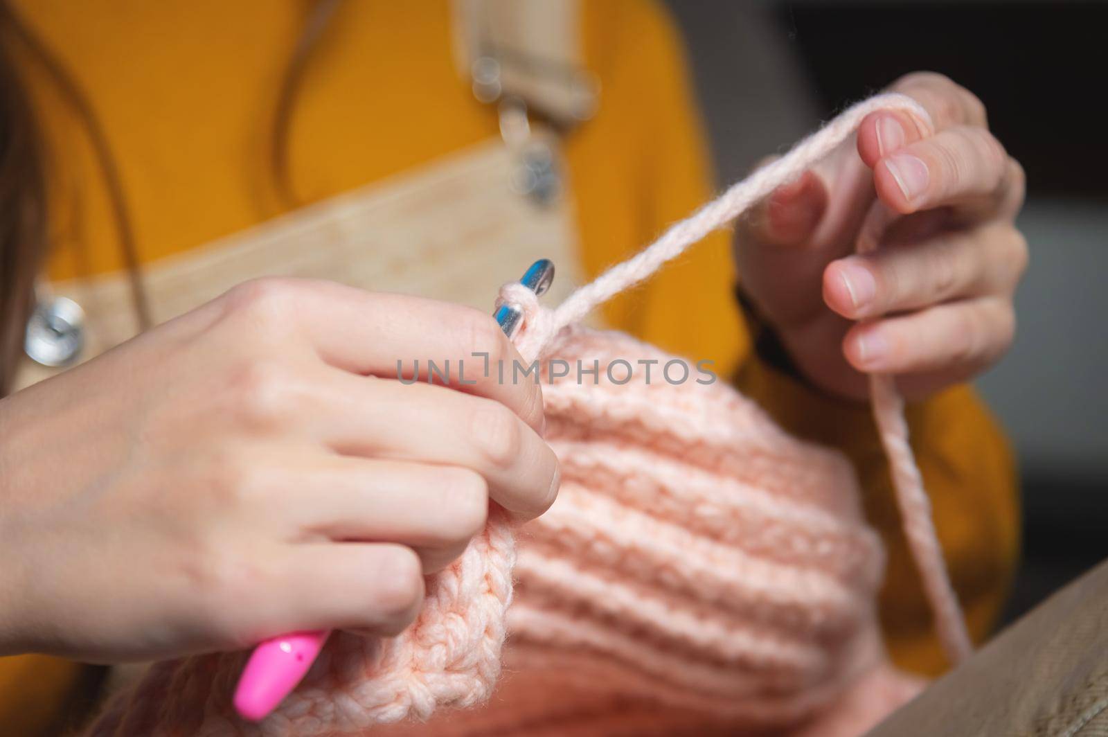female hands close-up, crocheting clothes on the sofa at home, handmade.