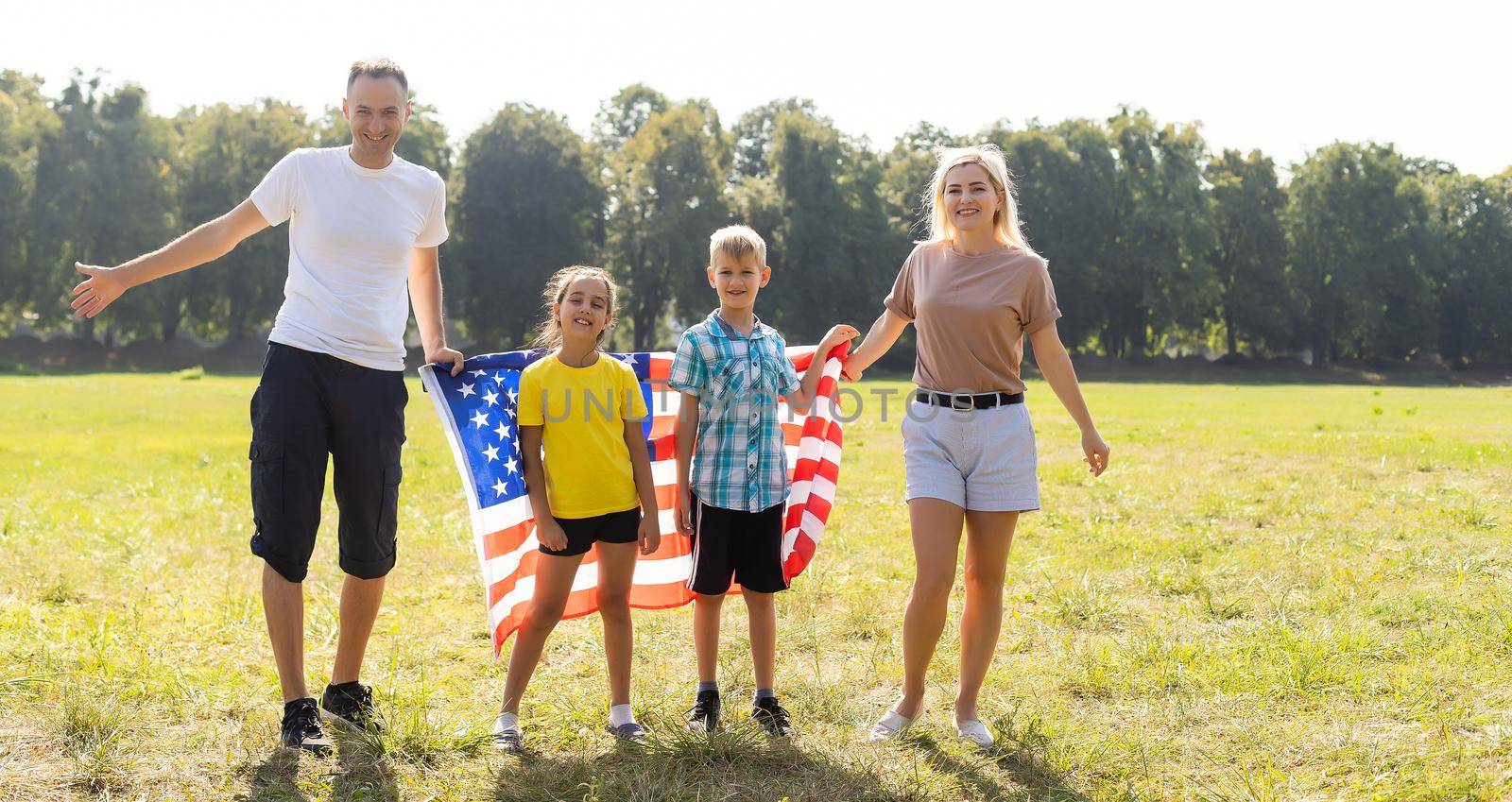 Beautiful family with the American flag in a field. Independence Day, 4th of July