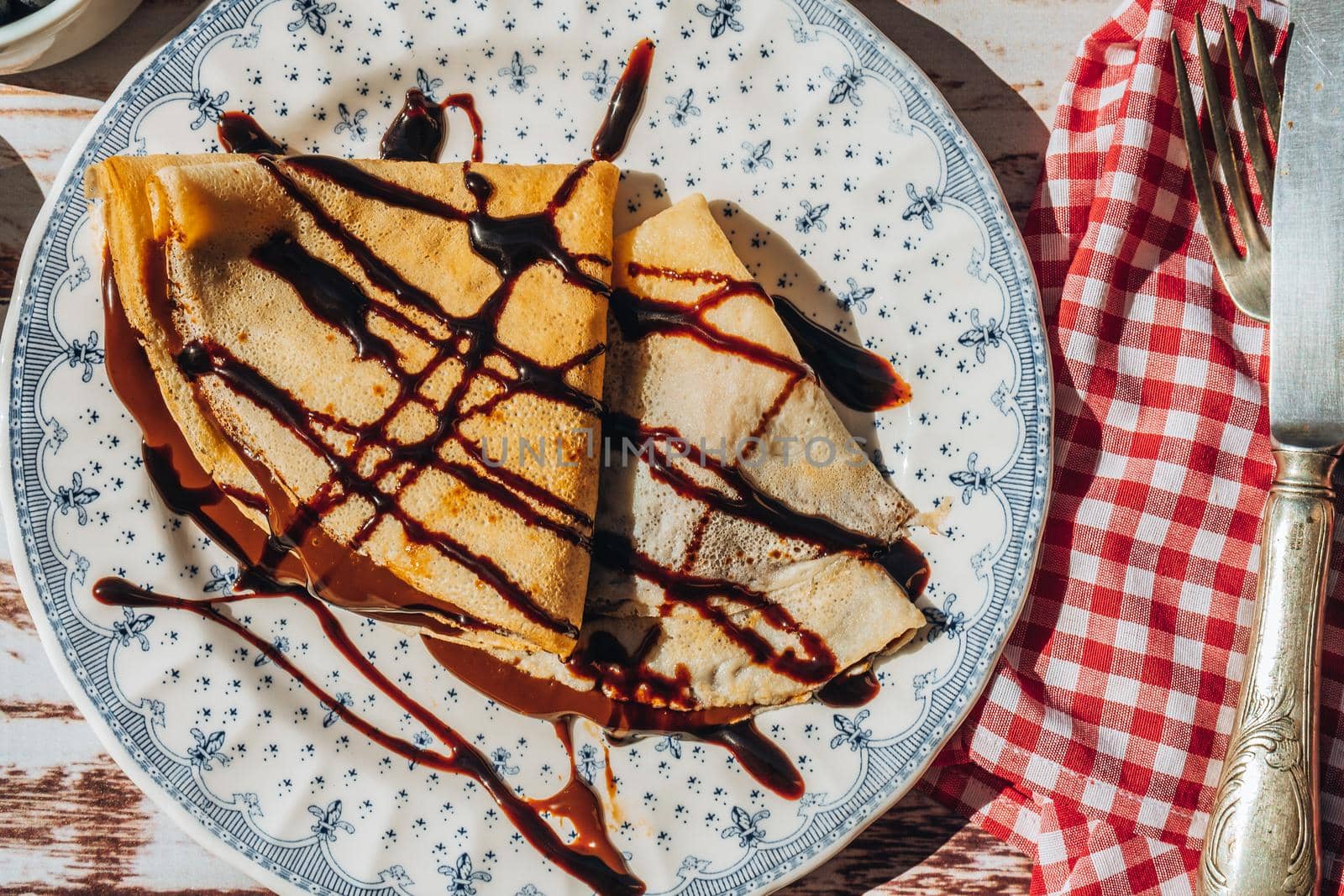 Plate two exquisite homemade pancakes or crepes filled with almond cream and chocolate with chocolate threads covering.