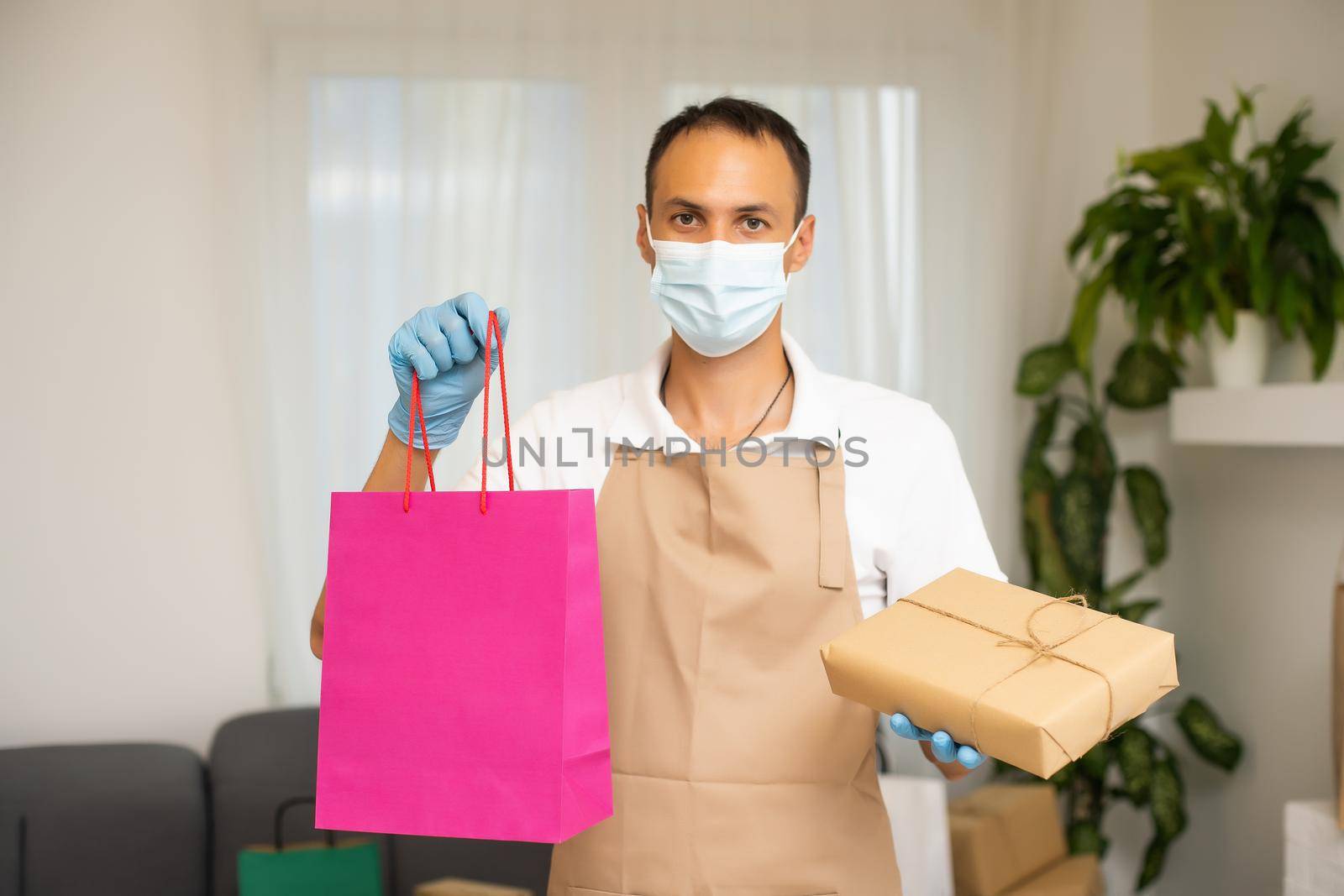 man in apron packaging products in paper bags for sale in workshop. Small business concept